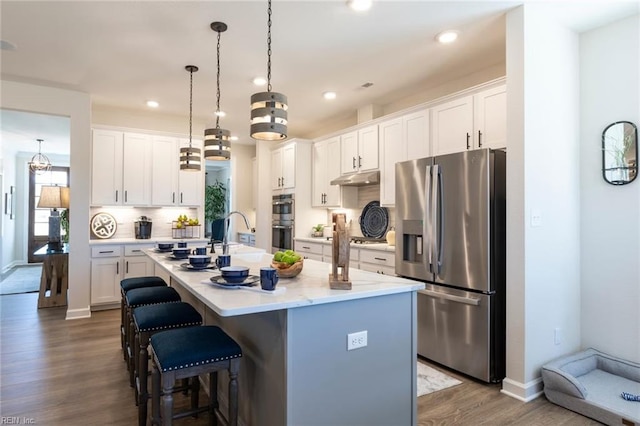 137 Preserve Way, Suffolk, VA 23434 - kitchen featuring appliances with stainless steel finishes, dark wood-type flooring, light countertops, a center island with sink, and a kitchen breakfast bar