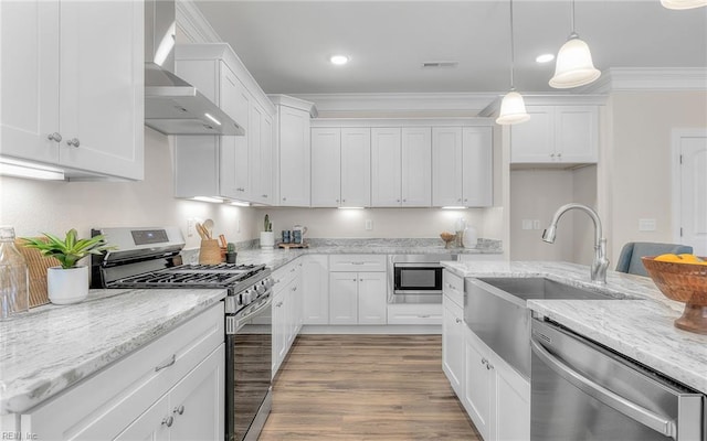 1608 Holland Ave, Norfolk, VA 23509 - kitchen featuring stainless steel appliances, wall chimney range hood, white cabinetry, hanging light fixtures, and light wood-type flooring