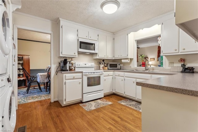105 Stavenger Ct, Williamsburg, VA 23188 - kitchen with white appliances, stacked washer and clothes dryer, a sink, light wood-type flooring, and a textured ceiling