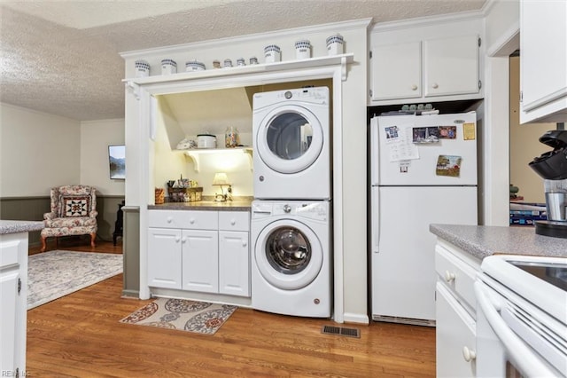 105 Stavenger Ct, Williamsburg, VA 23188 - washroom featuring stacked washer and clothes dryer, a textured ceiling, light wood-type flooring, and crown molding