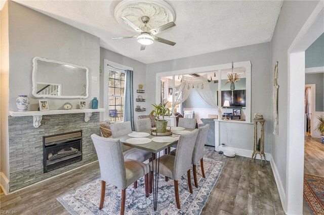 3317 Montana Ave, Norfolk, VA 23513 - dining area with wood finished floors, ceiling fan, a textured ceiling, a glass covered fireplace, and baseboards