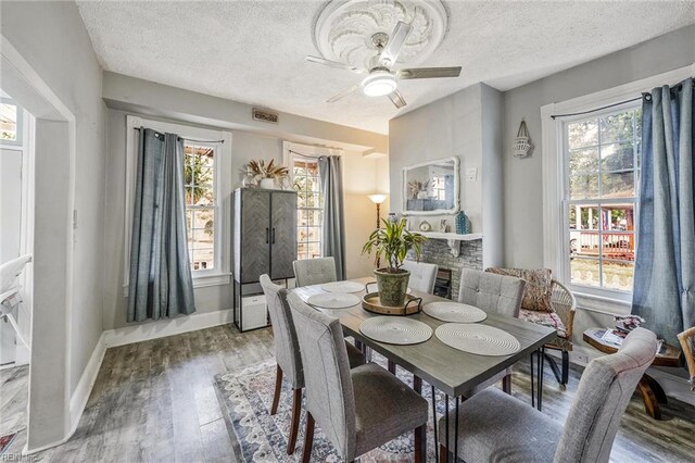 3317 Montana Ave, Norfolk, VA 23513 - dining room featuring wood finished floors, a textured ceiling, ceiling fan, a fireplace, and baseboards