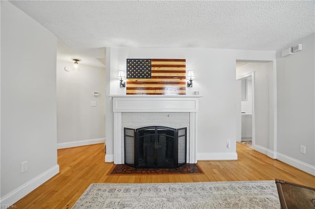 6223 Rolfe Ave, Norfolk, VA 23508 - unfurnished living room with wood finished floors, a brick fireplace, baseboards, and a textured ceiling