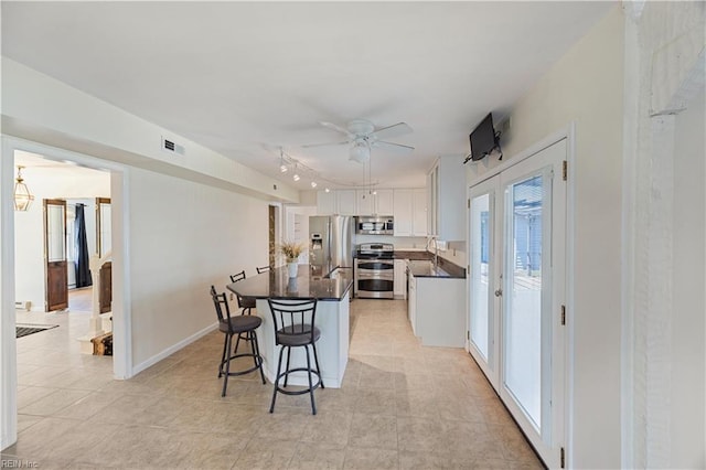 4456 Hudgins Dr, Virginia Beach, VA 23455 - kitchen featuring appliances with stainless steel finishes, dark countertops, white cabinets, ceiling fan, and a breakfast bar