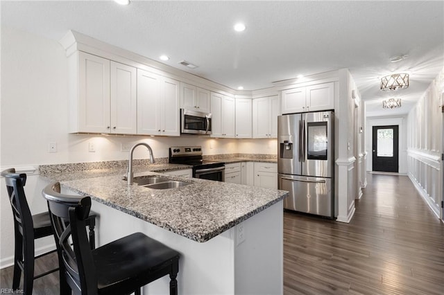 82 Beacon Rd, Portsmouth, VA 23702 - kitchen featuring stainless steel appliances, a sink, a peninsula, white cabinetry, and recessed lighting