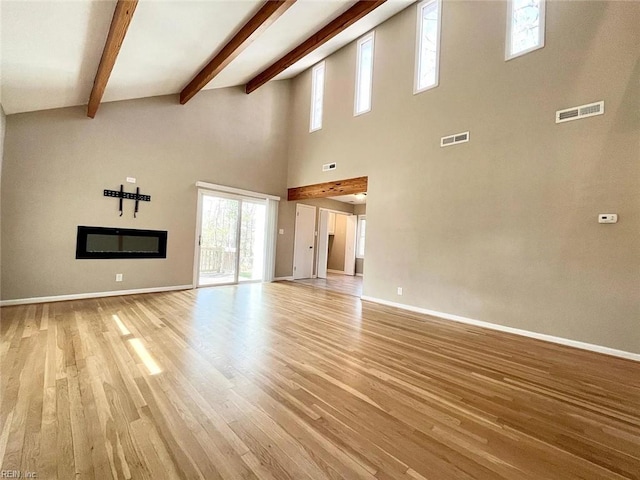 10104 Ogilvy Ln, Carrollton, VA 23314 - unfurnished living room featuring light wood finished floors, baseboards, beamed ceiling, and a high ceiling