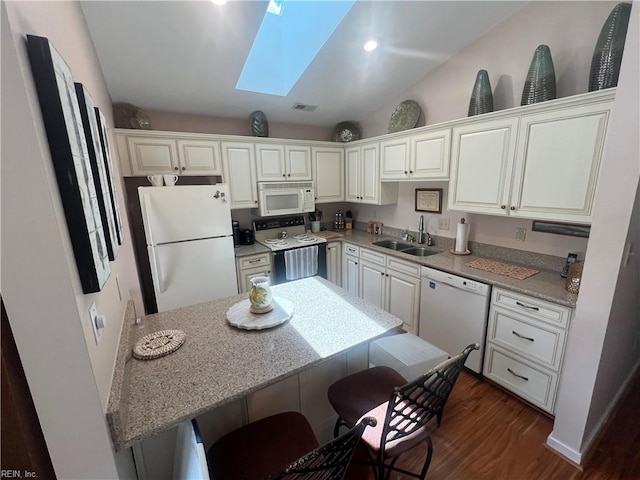 240 Dockside Dr Unit C, Hampton, VA 23669 - kitchen featuring white appliances, a sink, dark wood finished floors, a breakfast bar area, and a skylight