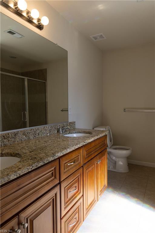 1932 Linster St, Chesapeake, VA 23324 - bathroom featuring double vanity, toilet, a stall shower, tile patterned floors, and baseboards