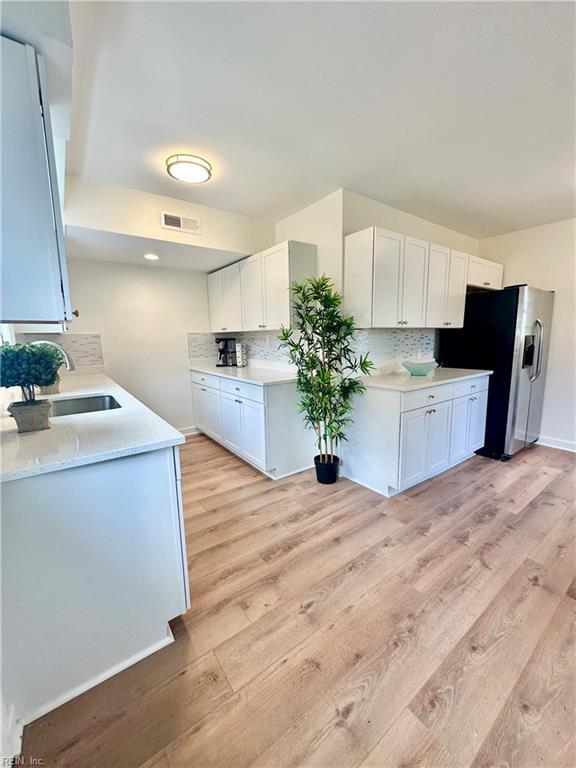 4863 Windermere Ave, Norfolk, VA 23513 - kitchen with a sink, stainless steel refrigerator with ice dispenser, light wood finished floors, tasteful backsplash, and white cabinets