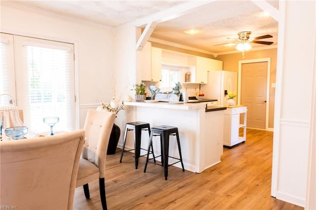 4505 Hessian Ct, Virginia Beach, VA 23462 - kitchen with white refrigerator with ice dispenser, ornamental molding, a breakfast bar, a ceiling fan, and a peninsula