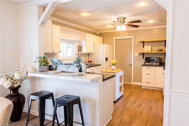 4505 Hessian Ct, Virginia Beach, VA 23462 - kitchen with white refrigerator with ice dispenser, a peninsula, open shelves, ceiling fan, and ornamental molding