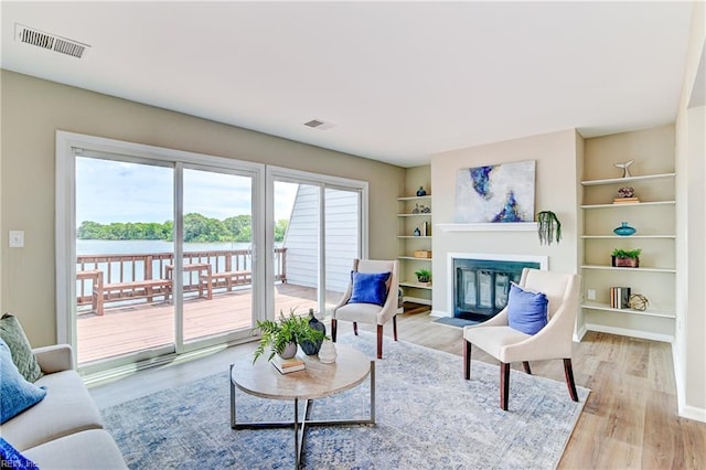 166 Mill Point Dr, Hampton, VA 23669 - living area featuring a fireplace with flush hearth, wood finished floors, a water view, built in features, and baseboards