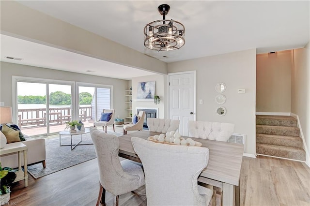 166 Mill Point Dr, Hampton, VA 23669 - dining room with a chandelier, light wood finished floors, stairway, baseboards, and a glass covered fireplace