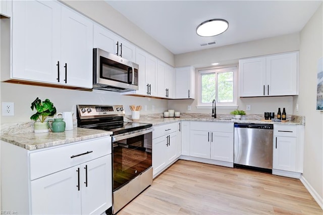 166 Mill Point Dr, Hampton, VA 23669 - kitchen featuring appliances with stainless steel finishes, a sink, light stone countertops, white cabinets, and light wood-type flooring