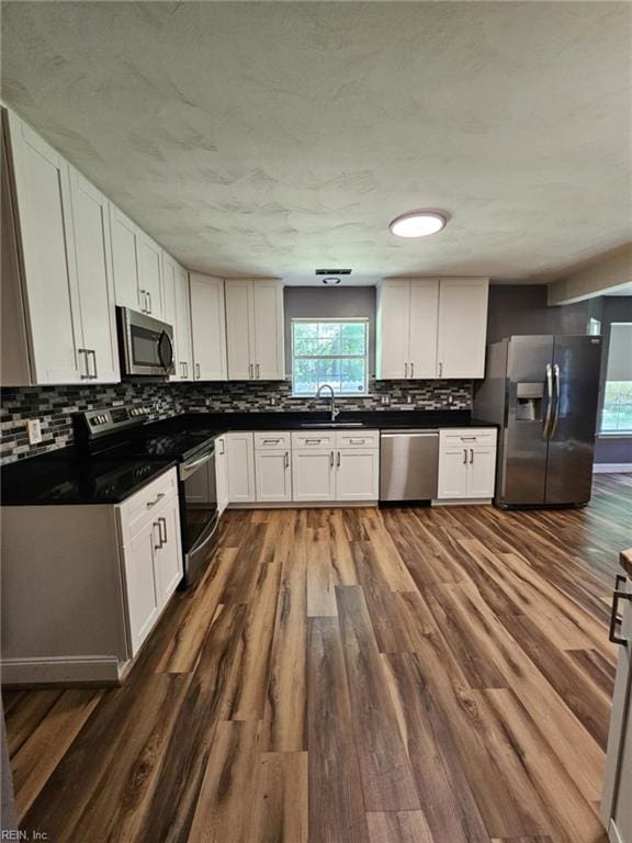 834 Haskins Dr, Suffolk, VA 23434 - kitchen featuring appliances with stainless steel finishes, dark countertops, a sink, decorative backsplash, and dark wood finished floors