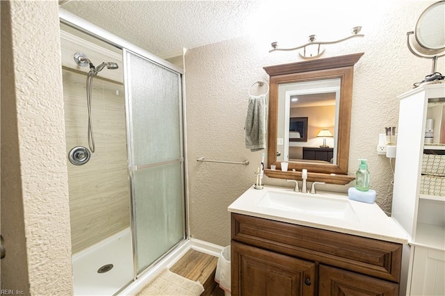14387 Tucker Swamp Rd, Zuni, VA 23898 - bathroom featuring a shower stall, vanity, wood finished floors, a textured wall, and a textured ceiling