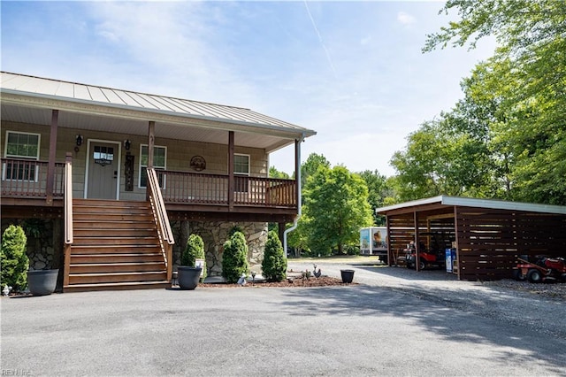 14387 Tucker Swamp Rd, Zuni, VA 23898 - view of front of house featuring a standing seam roof, stone siding, stairs, covered porch, and asphalt driveway