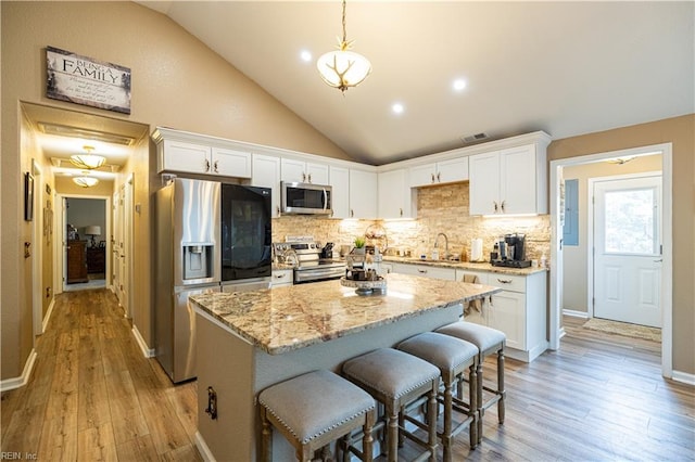 14387 Tucker Swamp Rd, Zuni, VA 23898 - kitchen featuring stainless steel appliances, lofted ceiling, white cabinets, light stone counters, and recessed lighting