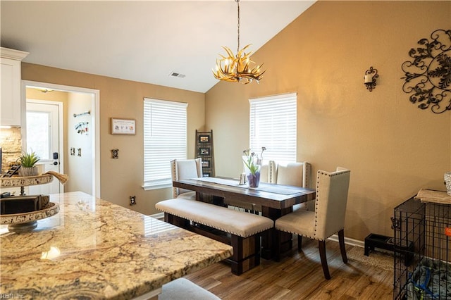 14387 Tucker Swamp Rd, Zuni, VA 23898 - dining area featuring dark wood-style floors, vaulted ceiling, and a chandelier