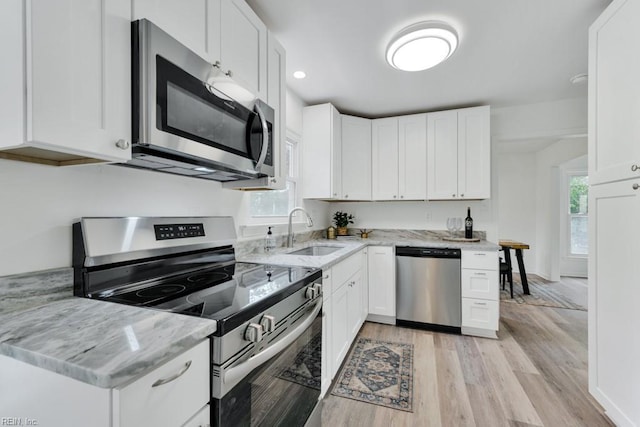 4401 Southampton Arch, Portsmouth, VA 23703 - kitchen featuring appliances with stainless steel finishes, a sink, light wood-style floors, white cabinetry, and light stone counters