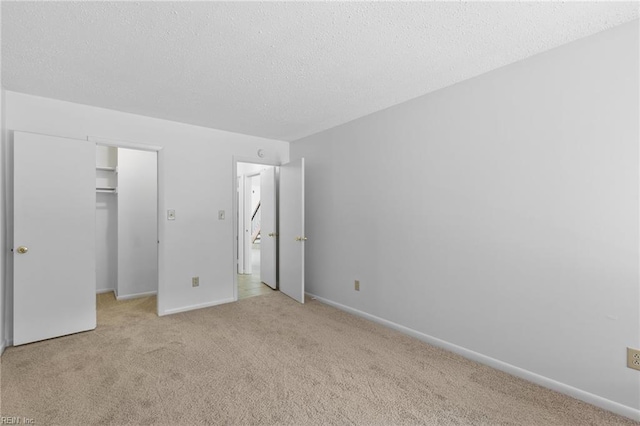 4321 Moosewood Ct, Virginia Beach, VA 23462 - unfurnished bedroom with light colored carpet, a walk in closet, a textured ceiling, a closet, and baseboards