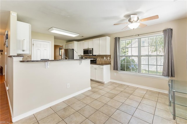 115 Rochdale Ln, Suffolk, VA 23434 - kitchen with appliances with stainless steel finishes, a breakfast bar area, ceiling fan, dark stone countertops, and a peninsula