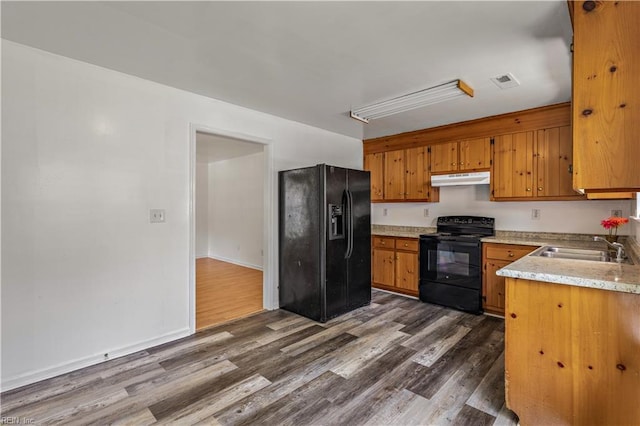 5036 John St, Chesapeake, VA 23321 - kitchen featuring black appliances, under cabinet range hood, dark wood-style flooring, and brown cabinetry