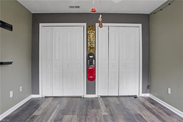 6412 Dove St, Norfolk, VA 23513 - unfurnished bedroom with dark wood-type flooring, two closets, and baseboards