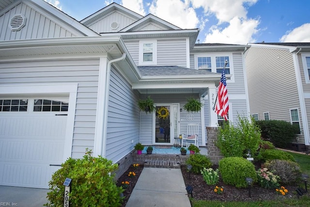 205 Markham St, Suffolk, VA 23435 - view of exterior entry with a porch, a garage, and roof with shingles