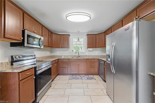 23 Stonewall Ter, Hampton, VA 23666 - kitchen featuring stainless steel appliances, brown cabinets, light stone counters, and a sink