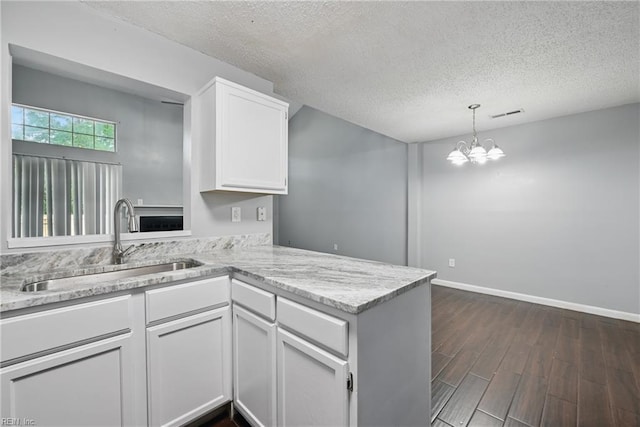 5101 Glenwood Way, Virginia Beach, VA 23456 - kitchen featuring a sink, white cabinets, a textured ceiling, a peninsula, and dark wood-style floors