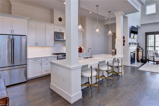 103 Enclave Ct, Williamsburg, VA 23185 - kitchen with premium appliances, a sink, under cabinet range hood, ornate columns, and a kitchen bar