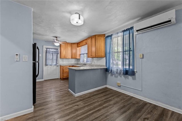 3505 Commonwealth Ave, Portsmouth, VA 23707 - kitchen featuring an AC wall unit, baseboards, dark wood finished floors, light countertops, and a peninsula