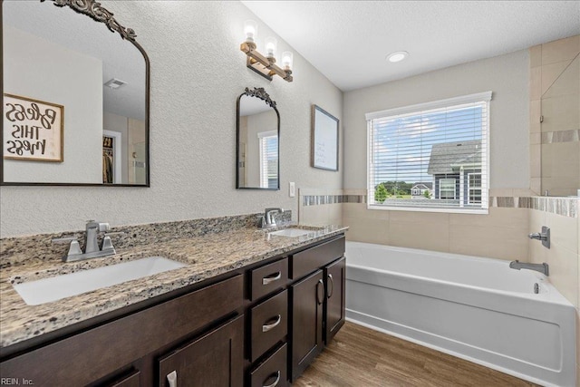 3012 George Starr Dr, Virginia Beach, VA 23456 - bathroom with a tub to relax in, wood finished floors, double vanity, a textured wall, and a textured ceiling
