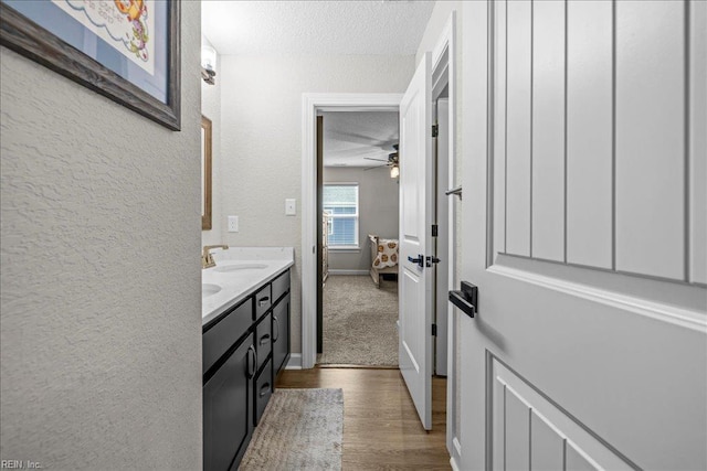 3012 George Starr Dr, Virginia Beach, VA 23456 - bathroom with a textured ceiling, a textured wall, wood finished floors, double vanity, and a ceiling fan