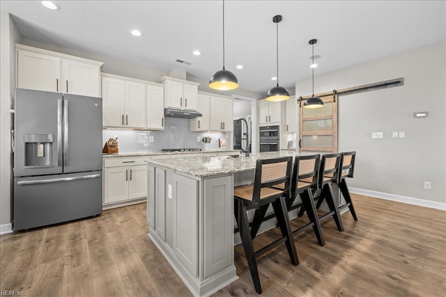 3012 George Starr Dr, Virginia Beach, VA 23456 - kitchen with stainless steel appliances, under cabinet range hood, baseboards, a barn door, and backsplash