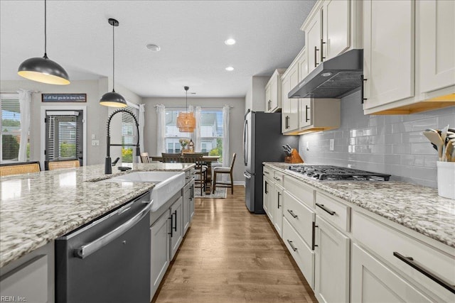 3012 George Starr Dr, Virginia Beach, VA 23456 - kitchen with appliances with stainless steel finishes, under cabinet range hood, a sink, wood finished floors, and backsplash
