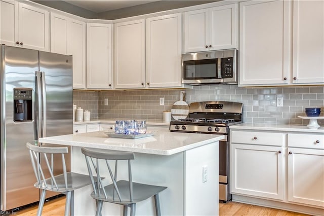123 Getty Rd, Suffolk, VA 23434 - kitchen with stainless steel appliances, a breakfast bar, white cabinets, a kitchen island, and decorative backsplash