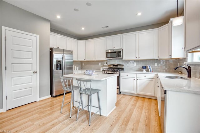 123 Getty Rd, Suffolk, VA 23434 - kitchen with appliances with stainless steel finishes, a sink, a center island, light wood finished floors, and decorative backsplash