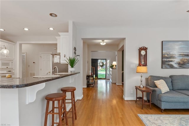 20185 Harbour Rdg, Smithfield, VA 23430 - kitchen with white appliances, a breakfast bar area, white cabinetry, light wood-type flooring, and recessed lighting