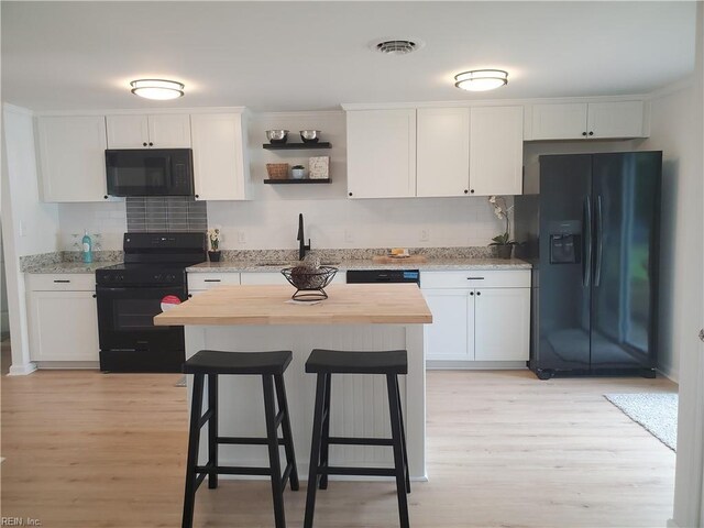 1215 Hale Dr, Hampton, VA 23663 - kitchen with black appliances, butcher block counters, tasteful backsplash, light wood-style floors, and a kitchen breakfast bar