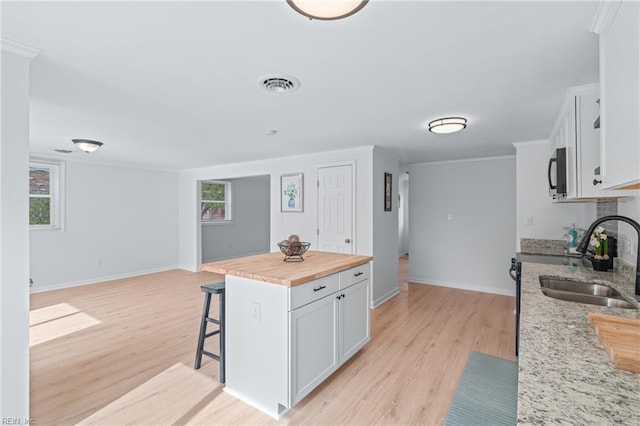 1215 Hale Dr, Hampton, VA 23663 - kitchen featuring a sink, butcher block countertops, a kitchen breakfast bar, light wood finished floors, and crown molding