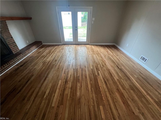 6217 Apple St, Suffolk, VA 23435 - unfurnished living room featuring wood finished floors, french doors, baseboards, and a brick fireplace