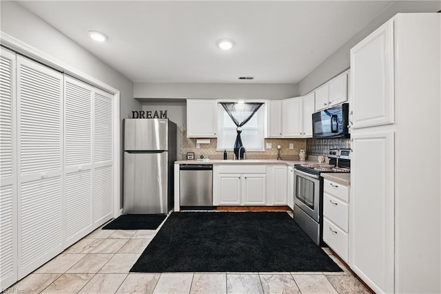 2405 Minnesota Ave, Norfolk, VA 23513 - kitchen with stainless steel appliances, tasteful backsplash, white cabinetry, light countertops, and a sink