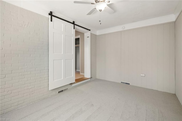 725 Lord Nelson Dr, Virginia Beach, VA 23464 - unfurnished bedroom featuring brick wall, carpet, a barn door, and ceiling fan