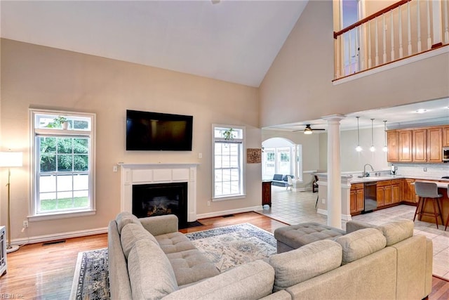 604 Schooner Blvd, Williamsburg, VA 23185 - living area featuring high vaulted ceiling, decorative columns, a fireplace with flush hearth, arched walkways, and baseboards
