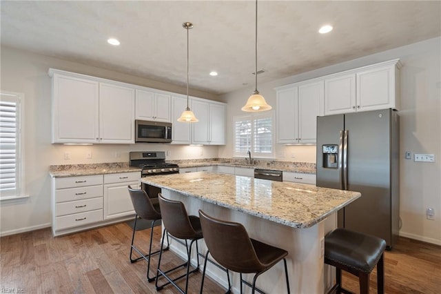 145 Beacon Run, Suffolk, VA 23435 - kitchen featuring appliances with stainless steel finishes, white cabinetry, a kitchen island, wood finished floors, and baseboards