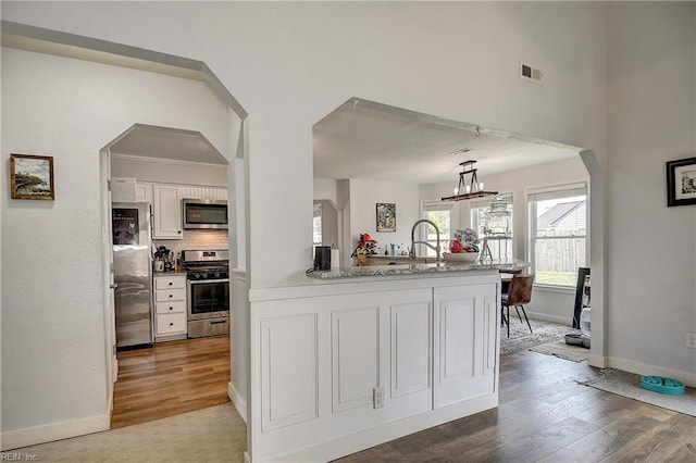 3145 Crestwood Ln, Virginia Beach, VA 23453 - kitchen with appliances with stainless steel finishes, white cabinetry, baseboards, wood finished floors, and arched walkways