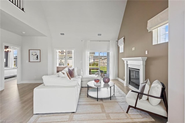 1284 Treviso Bay, Williamsburg, VA 23188 - living area featuring high vaulted ceiling, light wood-style flooring, plenty of natural light, a glass covered fireplace, and baseboards