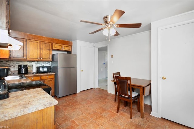 1204 Blythewood Ln, Suffolk, VA 23434 - kitchen with black appliances, wall chimney exhaust hood, brown cabinetry, a ceiling fan, and decorative backsplash